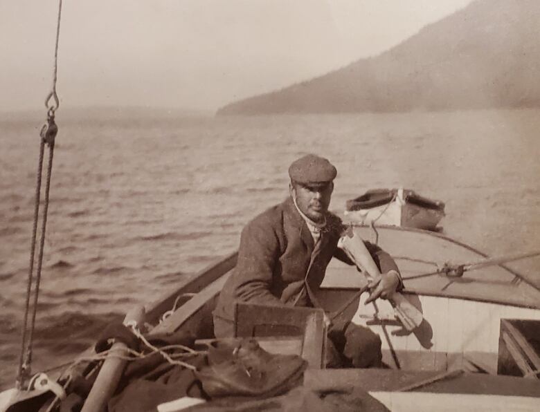 A man in a boat in a black-and-white photo.