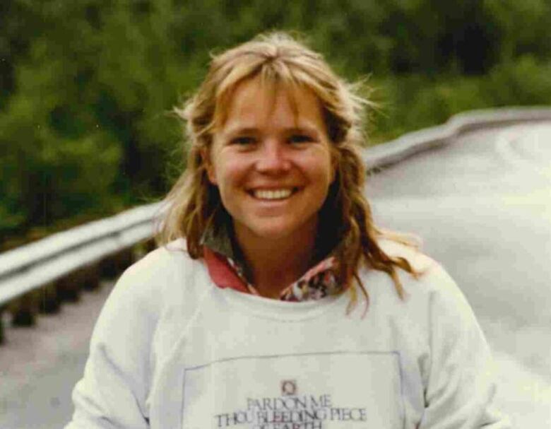 Portrait of a smiling woman standing at the side of the road.