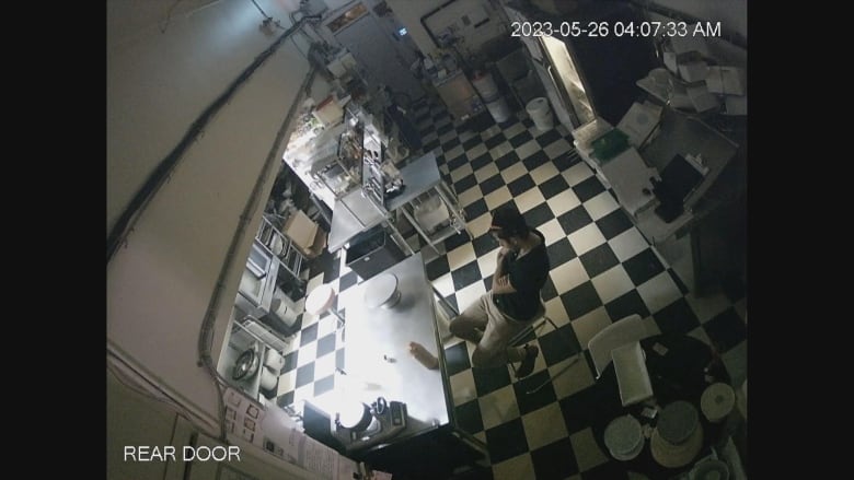 A man sits on a chair in a bakery. 