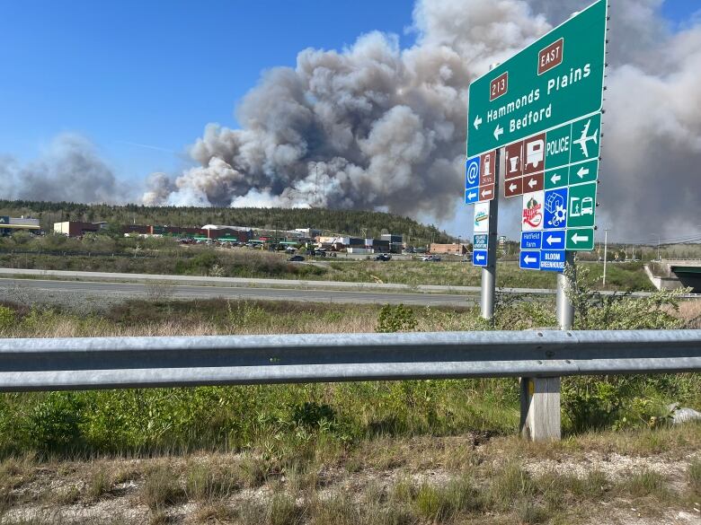 Photo of smoke over a wooded area with a Hammonds Plains and Bedford road sign in the foreground.