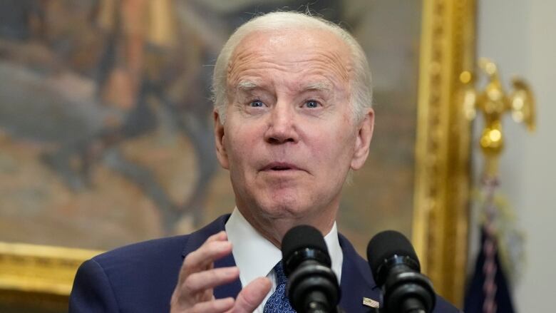 A person gestures while speaking into a microphone.