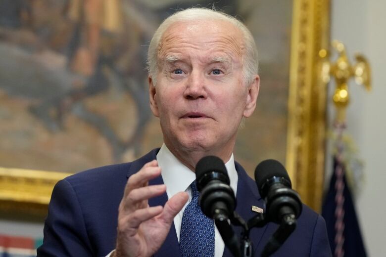 A person gestures while speaking into a microphone.