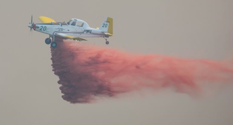 A small propeller plane with red substance dropping out the bottom