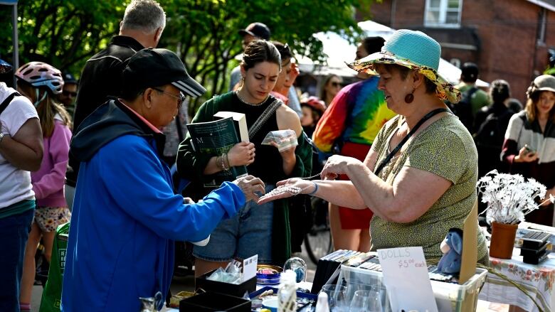 Someone is shown jewelry at a large, spring community yard sale.