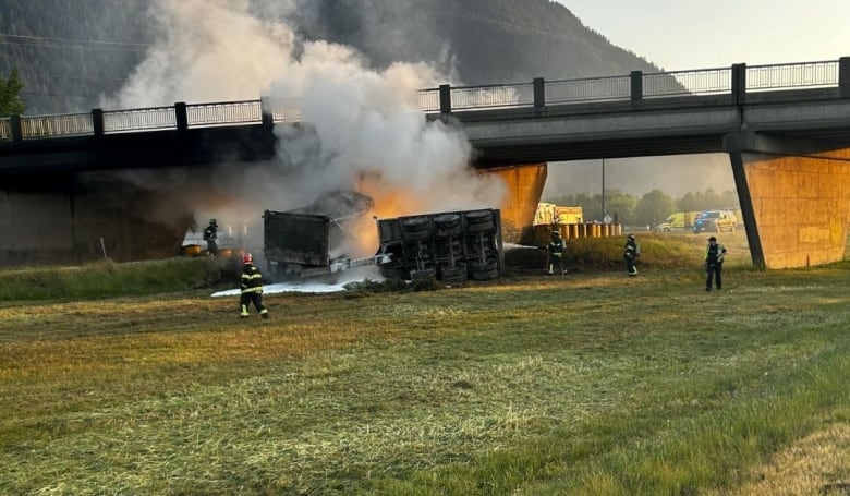 Firefighters fight a dump truck fire under an overpass