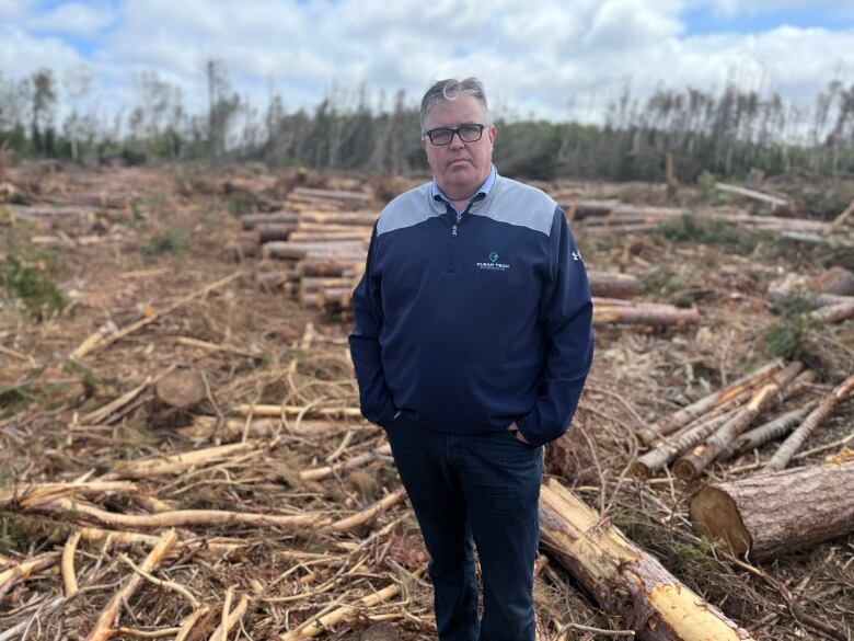 Environment Minister Steven Myers standing in field with downed trees.