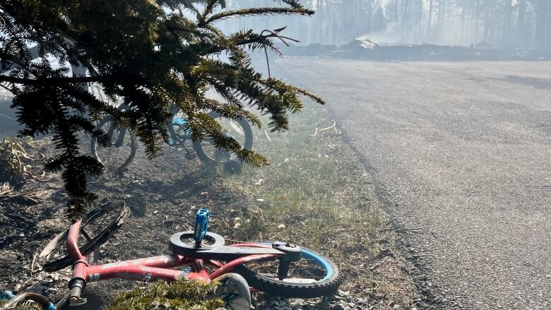 Two burned bikes are seen beside a driveway and the ruins of a home burned by fire.