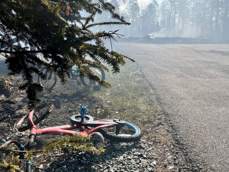 Two burned bikes are seen beside a driveway and the ruins of a home burned by fire.