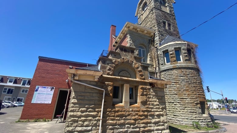 An outdoors shot of a stone historical building several stories tall, and the brick sidewalk in front of it.