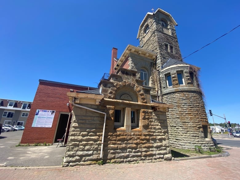 An outdoors shot of a stone historical building several stories tall, and the brick sidewalk in front of it.