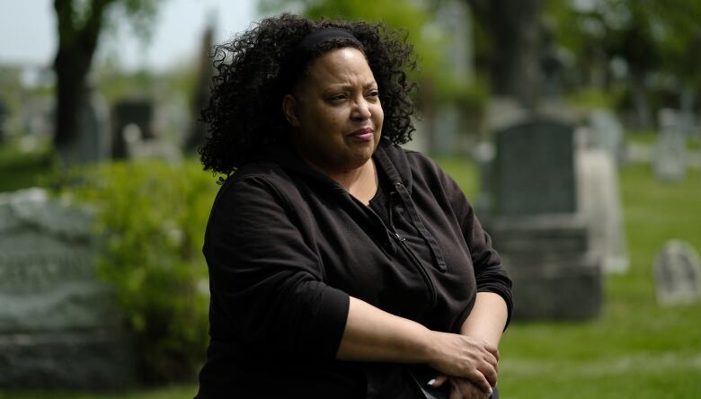 A Black woman gazes at the headstones in a cemetery.