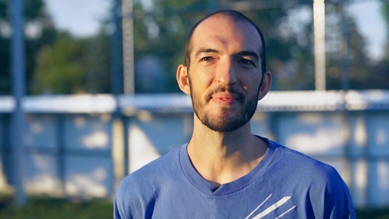 A close-up candid photo of a man dressed in a blue T-shirt. 