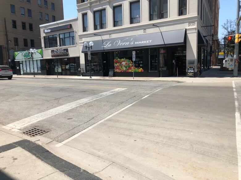 Roadway at the intersection of University Avenue and Pelissier Street, with businesses including La Vern's market in the background.