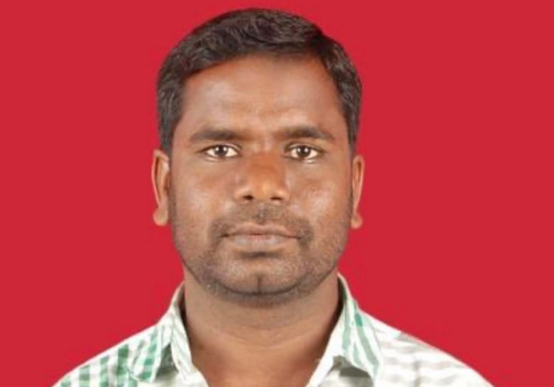 A man stands in front of a red background.