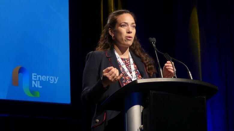 A woman stands at a podium in front of a crowd.