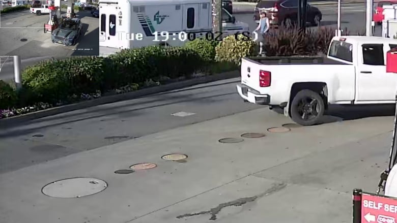 Surveillance camera footage of a man in a blue tank top walking past a gas station.