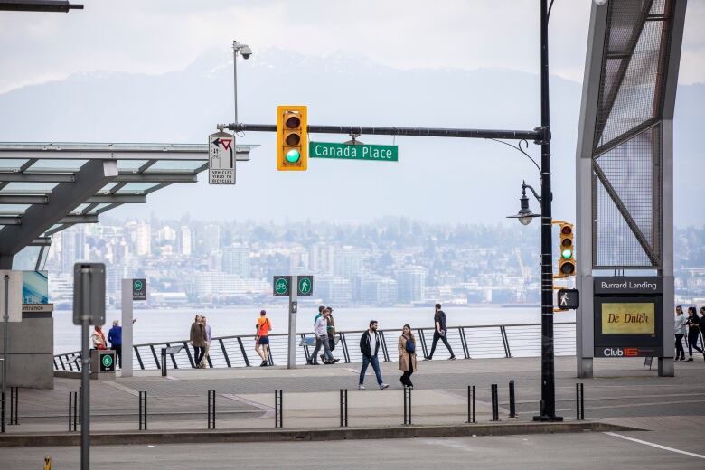 A number of people walk past a waterfront area in Vancouver.