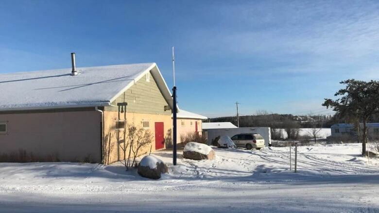 A yellowish and green church building is pictured on a snowy day.