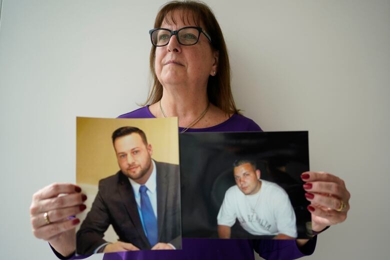 A woman holds two photographs of her sons.