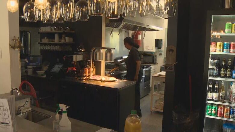 A person cooks food in a restaurant kitchen.