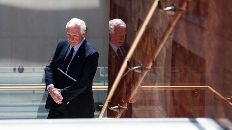 David Johnston, wearing a dark suit, stands in a stairwell on Parliament Hill.