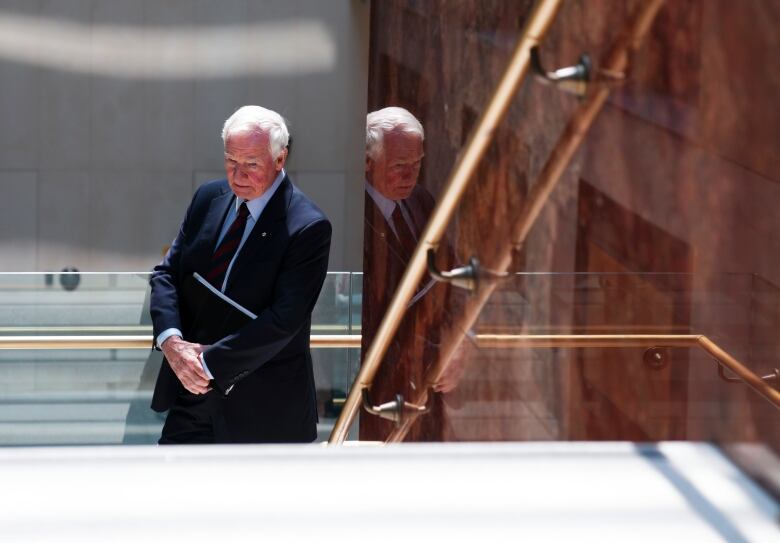 David Johnston, wearing a dark suit, stands in a stairwell on Parliament Hill.