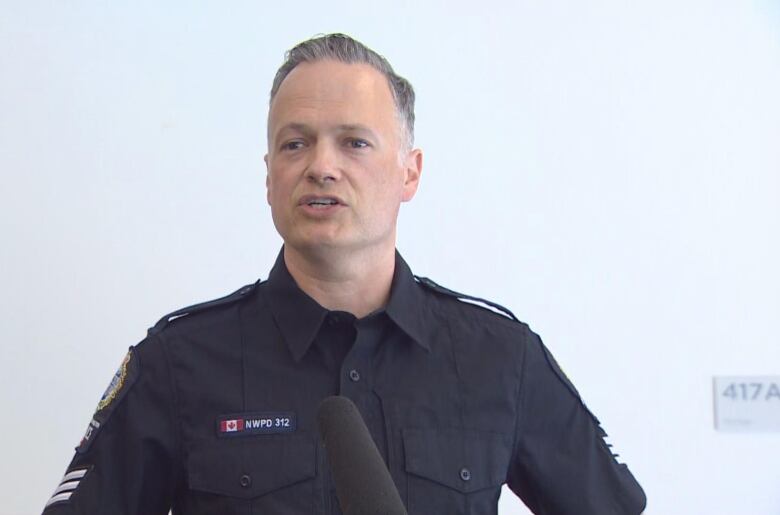 A white man wearing a police uniform speaks to a camera.