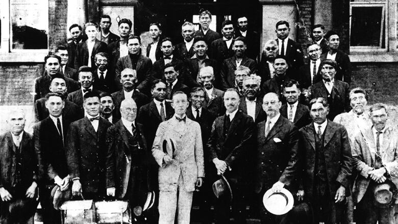 Forty-three men in suits stand on the stairs outside of Vancouver's Department of Indian Affairs building in July 1923, two holding briefcases. They include chiefs and delegates from 16 Swxw7mesh (Squamish) communities, as well as several Canadian government representatives at the front and centre.