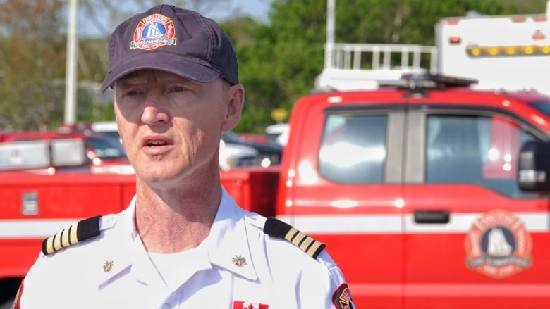 A main wearing a white collared shirt and a blue ballcap with the Halifax Fire logo stands in front of a red truck.