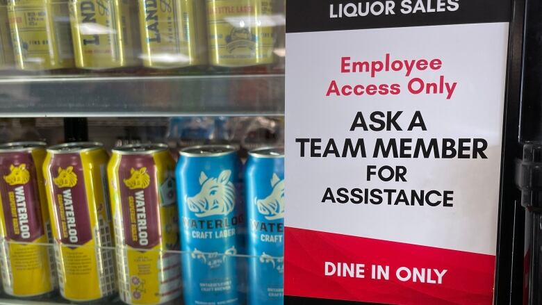 Poster saying 'Liquor Sales. Employee Access Only. Ask a Team Member For Assistance.' on a fridge with beer at a 7-Eleven store. 