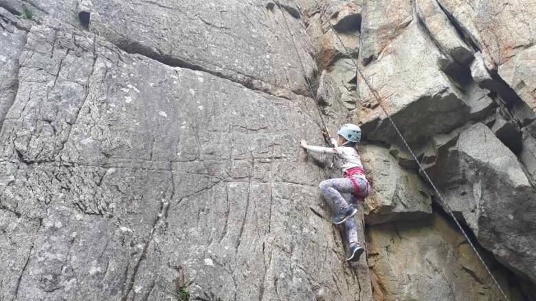 A rock climber is seen scaling a rock face.