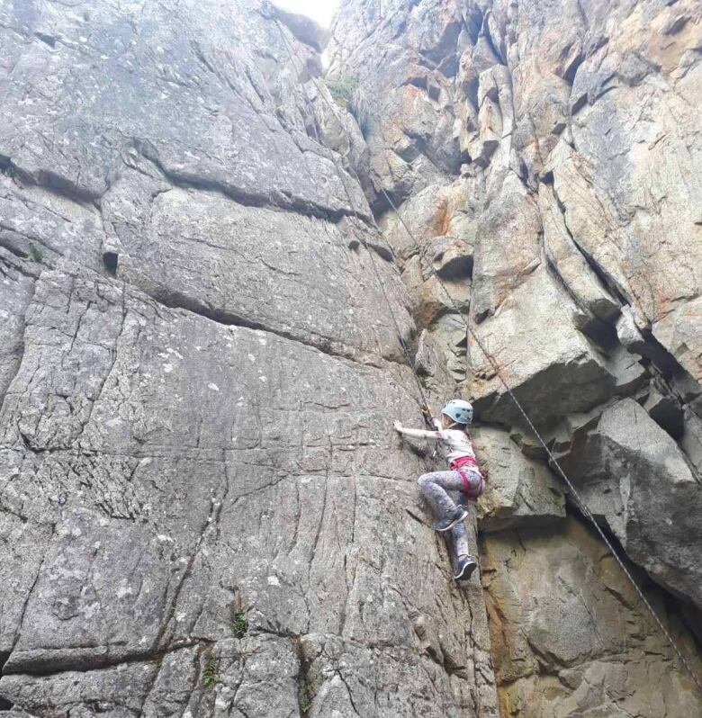 A rock climber is seen scaling a rock face.