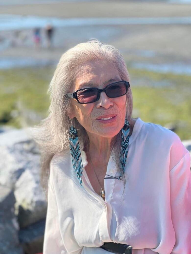 A woman with grey hair and a white shirt smiles