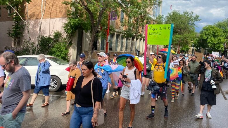 People in pride colours march in the rain. 