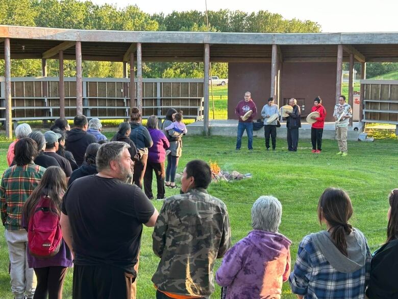 Group gathers in around a fire and in front of dummers.