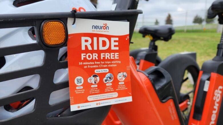 Close-up shot of a black and orange e-bike with a sign that reads, 