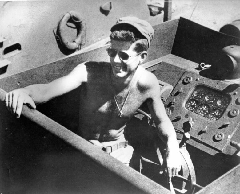 A black and white photo of a young JFK sitting atop a boat