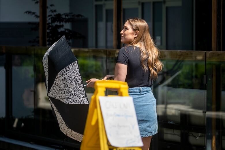 A woman uses an umbrella to protect herself from a crow during nesting season in Vancouver, British Columbia on Friday, June 2, 2023. 