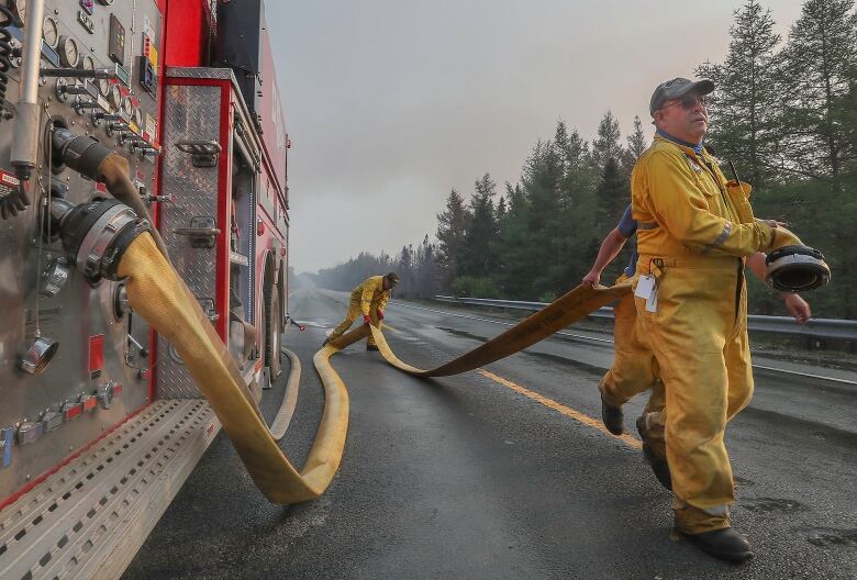 Firefighters run a hose at a wildfire scene