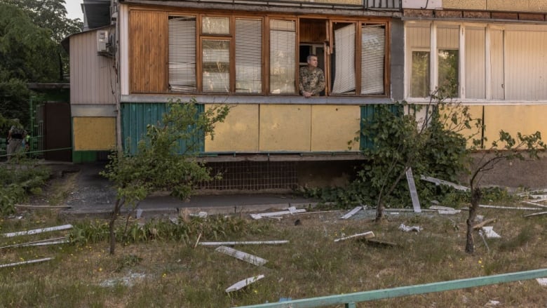 A man looks through the window of a missile-damaged building in Kyiv, Ukraine.