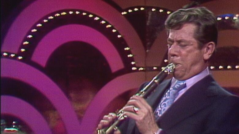 A jazz musician, Phil Nimmons, plays his clarinet during a solo in one of his songs on television.