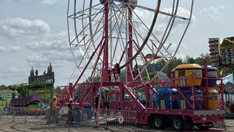 Men in construction gear at a ferris wheel in Stony Plain. Other rides can be seen in the background.