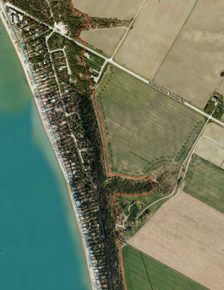 An aerial shot of lake huron, sand, a strip of homes and cottages, forests and fields. 