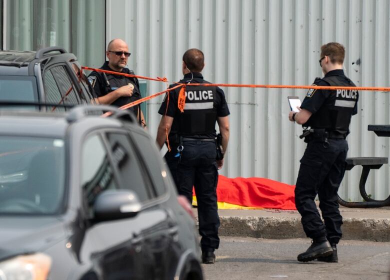 Many police officers with a body covered in the background.