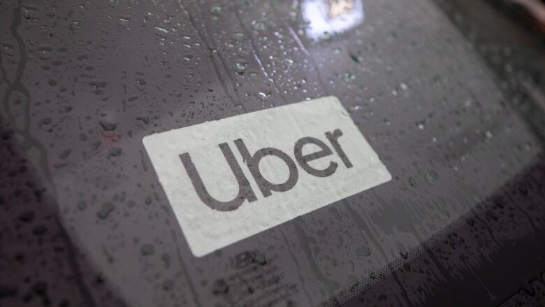 A rainy car dashboard with an 'Uber' sticker on it.