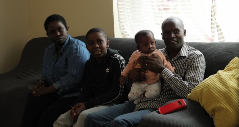 A family sits together on the couch watching television.