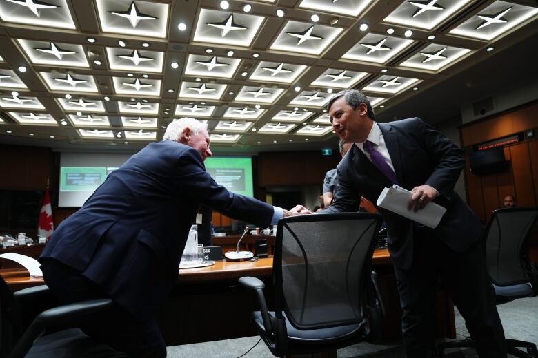 David Johnston, Independent Special Rapporteur on Foreign Interference, left, shakes hands with Conservative MP Michael Chong, before appearing as a witness at the Procedure and House Affairs Committee in Ottawa on Tuesday, June 6, 2023. 