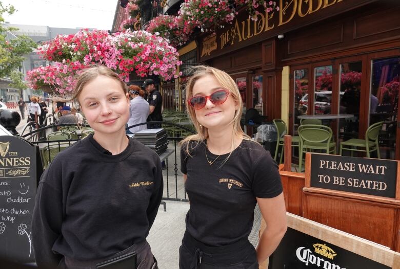 A waitress and a hostess stand at the entrance to a pub in Ottawa's Byward Market.