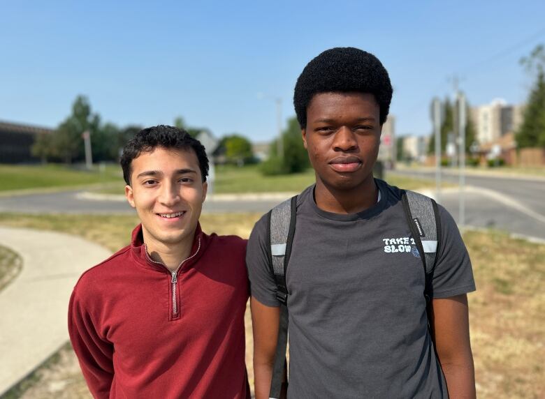 two teen boys stand outside a school