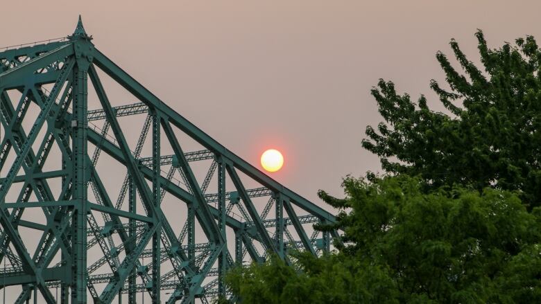 orange sun behind bridge in Montreal